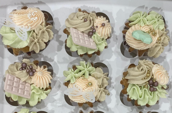 Decorative cupcakes with green and beige frosting in a box